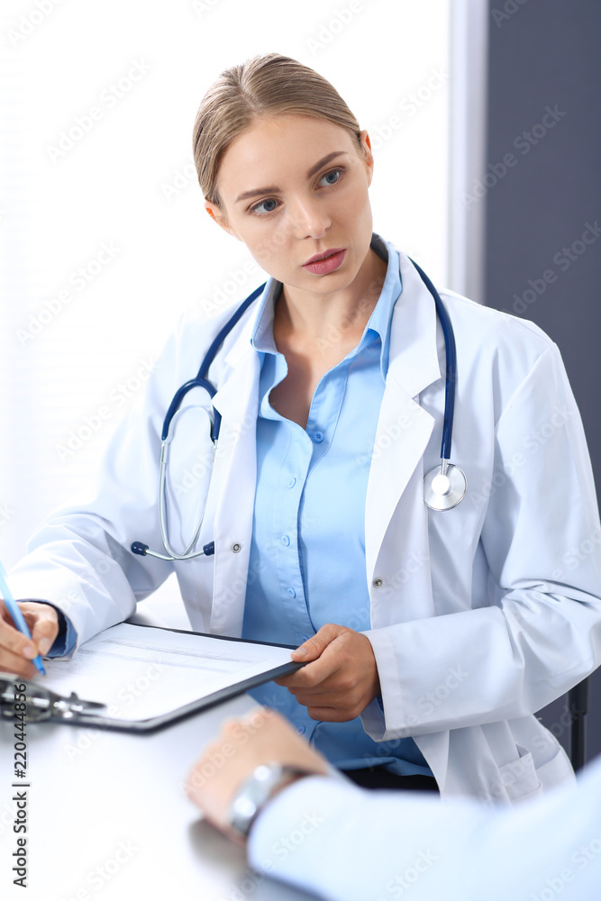 Doctor and patient in hospital. Beautiful blonde physician consulting business man about his health. Medicine concept Doctor and patient in hospital. Beautiful blonde physician consulting business man about his health. Medicine concept