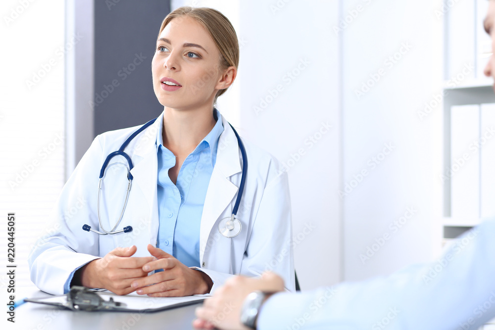 Doctor and patient in hospital. Beautiful blonde physician consulting business man about his health. Medicine concept