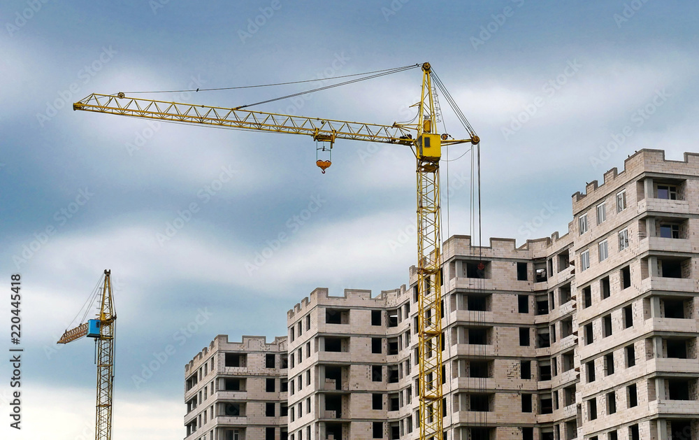 Two cranes and concrete building. Construction site background.