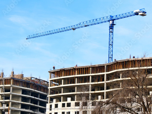 Big construction crane near building. Concrete building under construction. Building site.