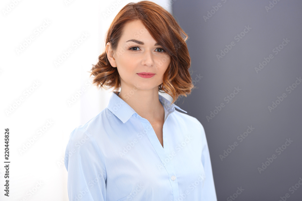 Young brunette business woman looks like a student girl working in office. Caucasian girl standing straight Young brunette business woman looks like a student girl working in office. Caucasian girl standing straight