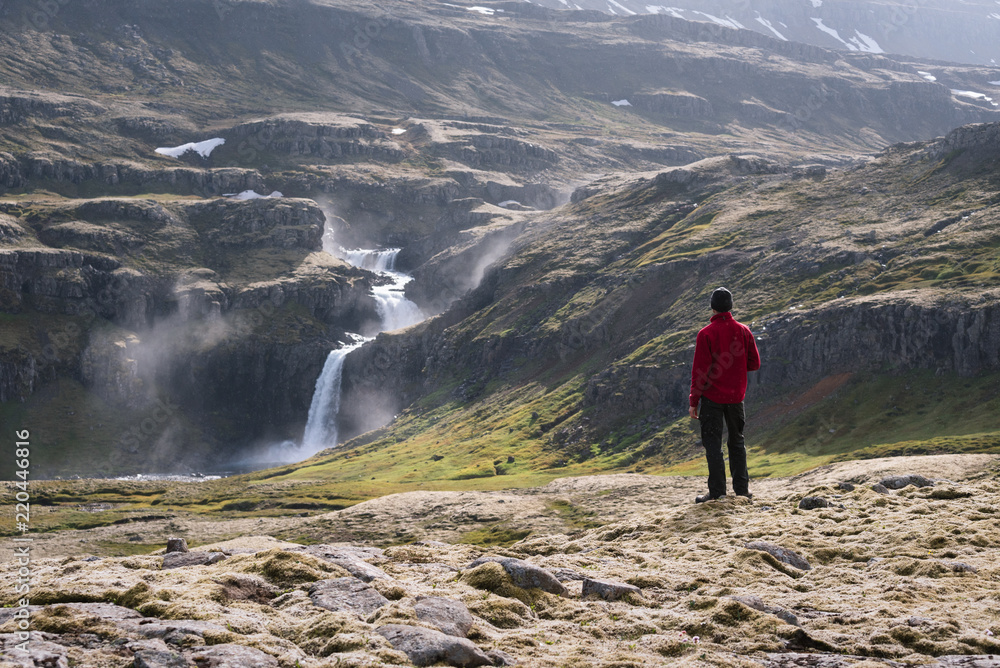 Tourist looks at a waterfall in Iceland Tourist looks at a waterfall in Iceland