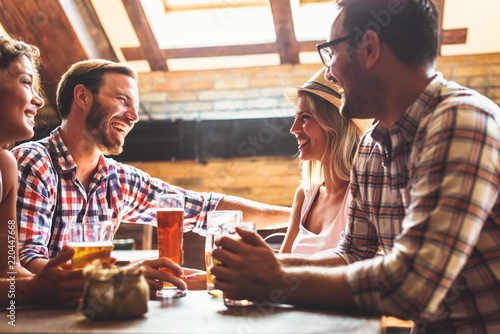 Canvas Print Happy friends having fun at bar - Young trendy people drinking beer and laughing