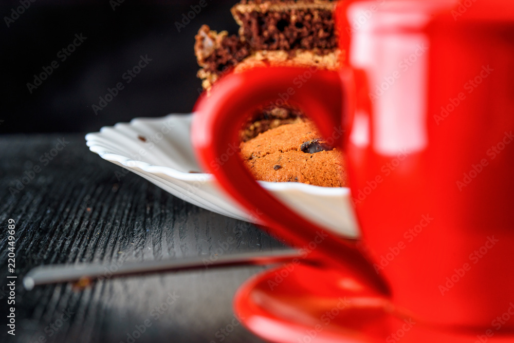 a piece of chocolate cake and cookies with chocolate on a red plate on a dark wooden background. Homemade baking.Close-up view. a piece of chocolate cake and cookies with chocolate on a red plate on a dark wooden background. Homemade baking.Close-up view.
