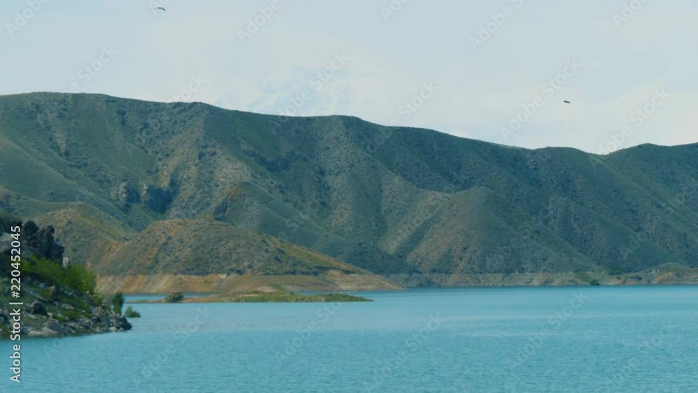 Birds fly above water surface of reservoir on river in armenian mountains Birds fly above water surface of reservoir on river in armenian mountains