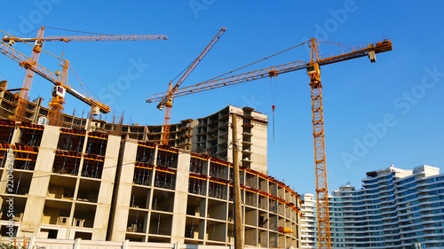 Big construction site. Four tower cranes near concrete building. Skyscraper construction.