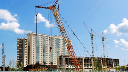 Commrcial building project. Construction site. Three construction cranes near concrete building.