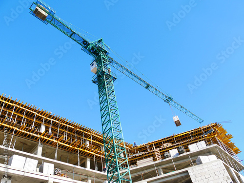 The crane lifts the load with concrete blocks.Construction site with hoisting crane and building.Scaffolding.