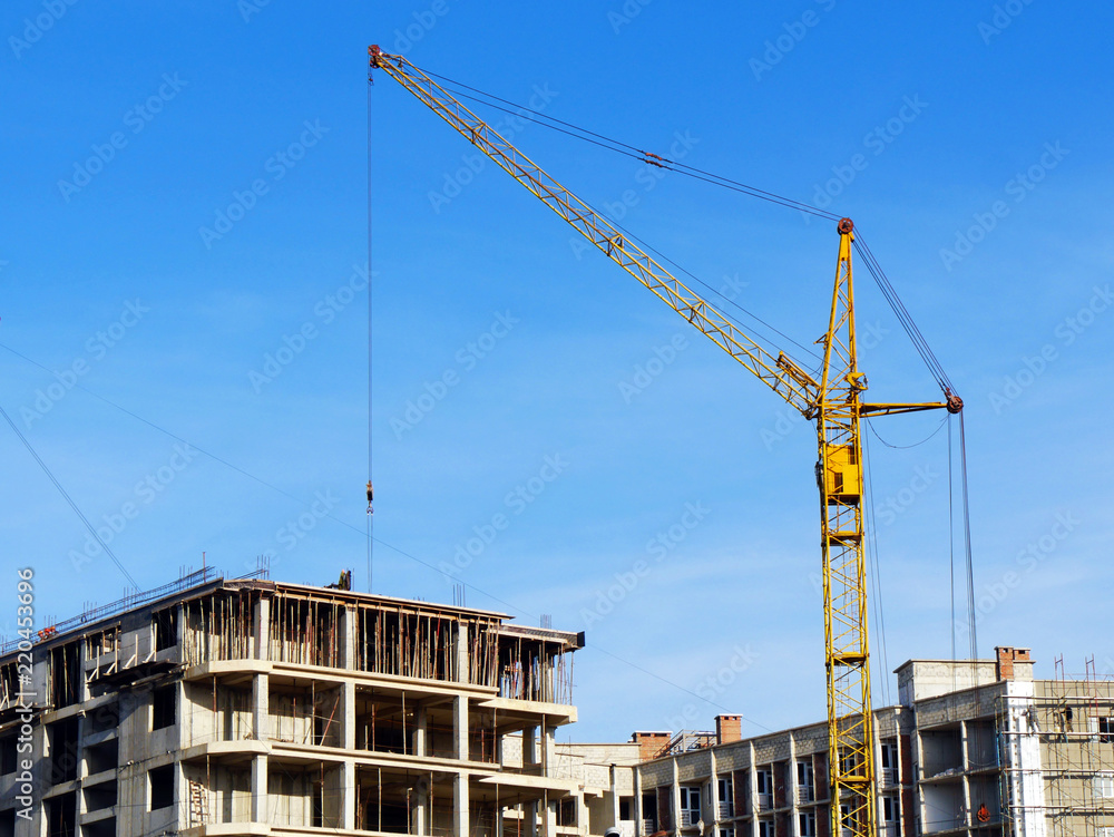 Crane near building. Concrete building under construction. Construction site.
