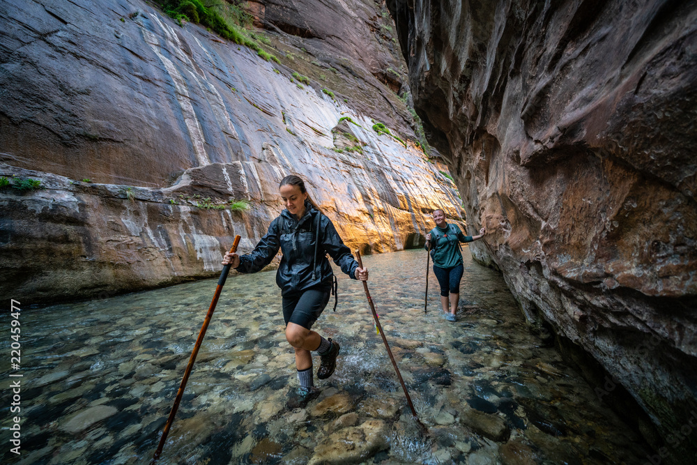 Two Young Female Friends Hiking Through the Narrows, Zion National Park, Utah - USA