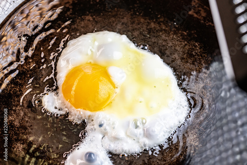 An egg frying in butter and oil in a carbon steel skillet