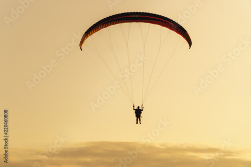 silhouette of paraplane on evening sky background, sunset time.