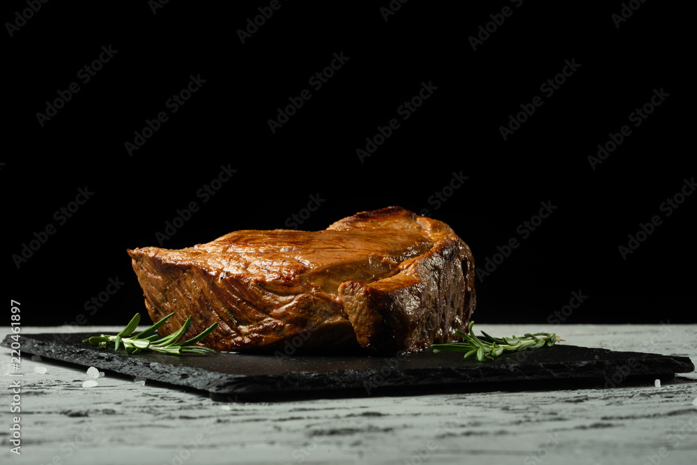 Beef steak with rosemary on a black background with open space for text design or restaurant menus. Horizontal photo Black text area.