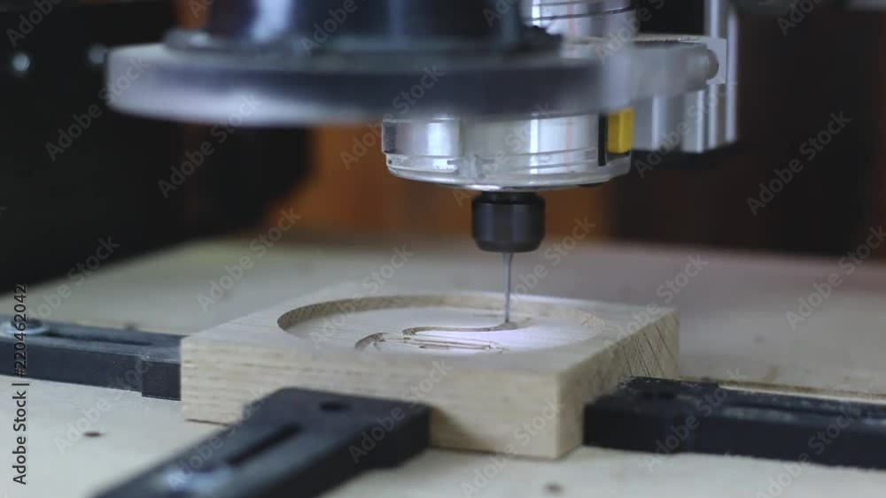A CNC Machine cuts into oak wood. Carving a 3D Model of a coffee cup into the oak wood. High Key lighting and shallow depth of field. A CNC Machine cuts into oak wood. Carving a 3D Model of a coffee cup into the oak wood. High Key lighting and shallow depth of field.