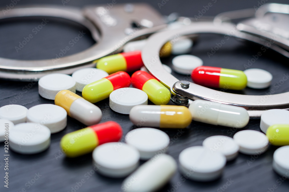 Handcuffs and pills and drugs on wooden table Handcuffs and pills and drugs on wooden table