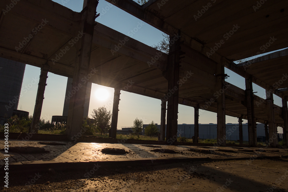 A deserted industrial plant site with old deserted structure on a beautiful sunset.
