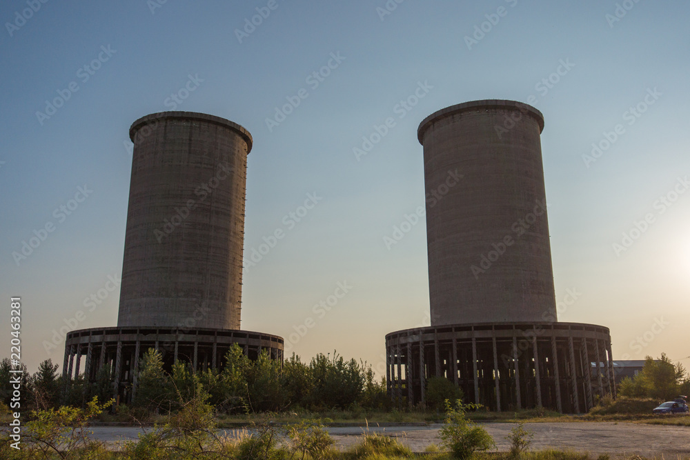 A deserted industrial plant site with big towers on a beautiful sunset.