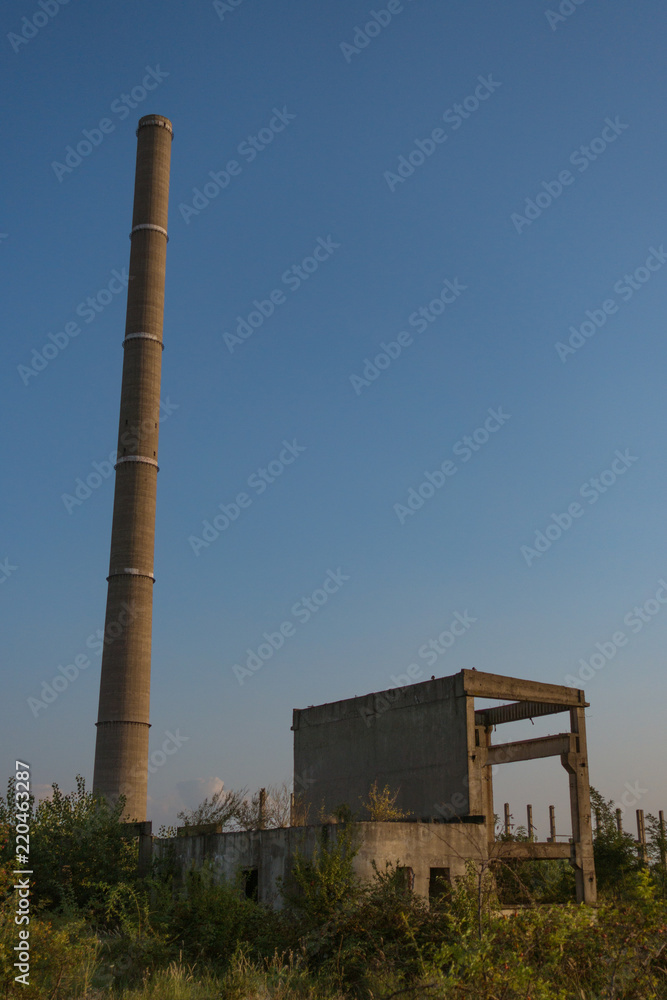 A deserted industrial plant site with big towers on a beautiful sunset.