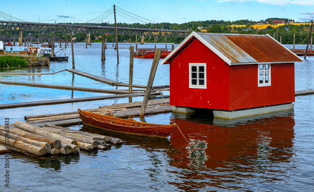 Old wooden boat and red cottage on water