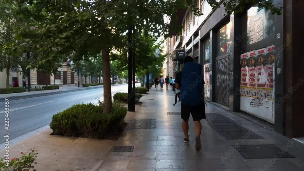 Backpacker walks down on the main road of Granada, Spain. Backpacker walks down on the main road of Granada, Spain.