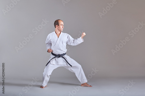 Sportsman in karategi and with a black belt does formal karate exercises