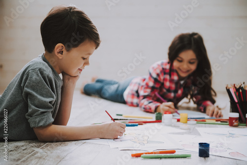 Cute Siblings Drawing Pictures Laying at Floor