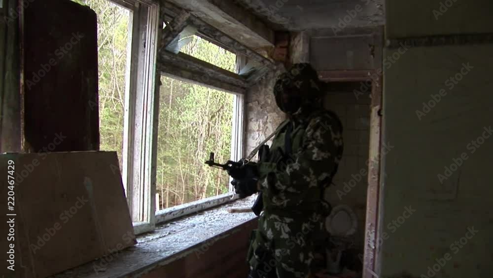 Airsoft player is in position is in a destroyed house. Sports team game using a copy of a firearm. People in military uniforms with weapons at the exercises. Airsoft player is in position is in a destroyed house. Sports team game using a copy of a firearm. People in military uniforms with weapons at the exercises.
