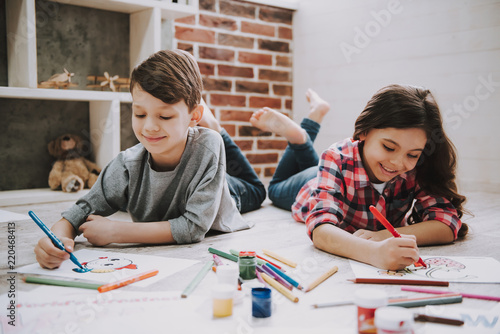 Cute Siblings Drawing Pictures Laying at Floor