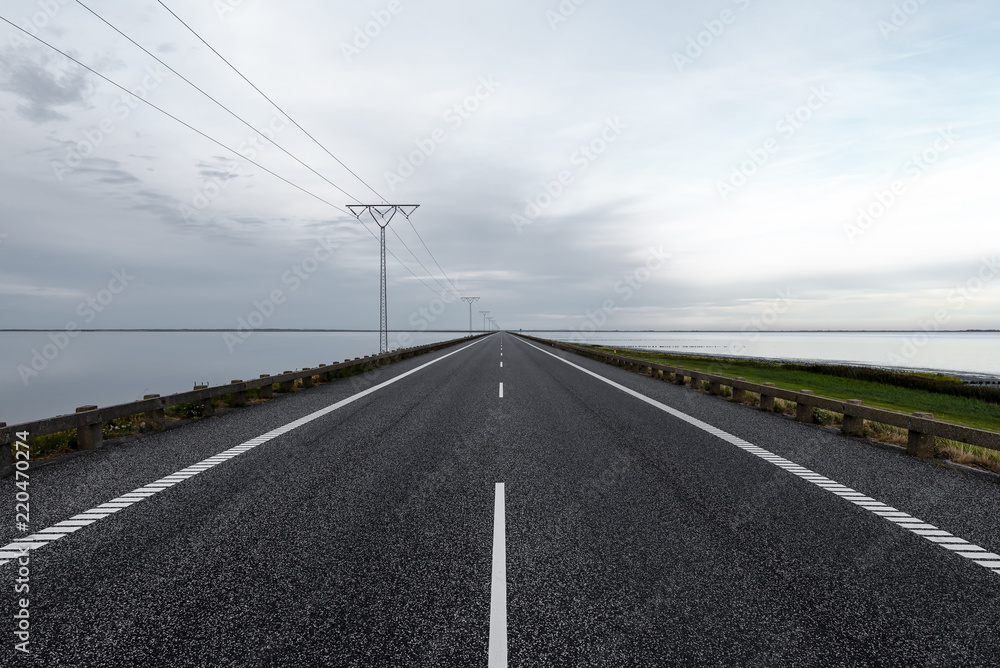 Long straight causeway with power line in Denmark