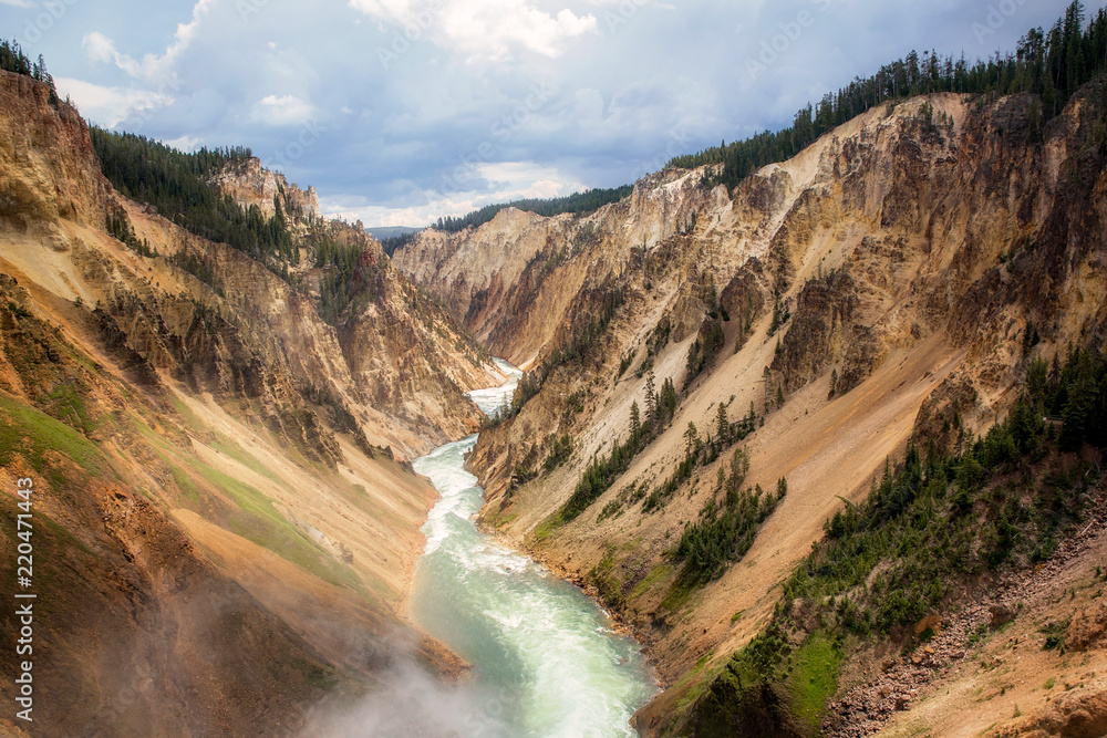 View from the top of a canyon ov powerful flowing stream from waterfall between mountains at Yellowstone National Park