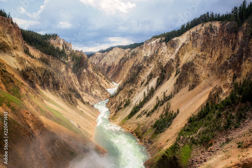 View from the top of a canyon ov powerful flowing stream from waterfall between mountains at Yellowstone National Park