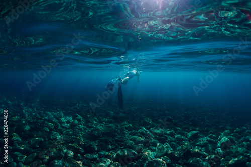 Freediver swim in ocean, underwater photo with sunlight and depth