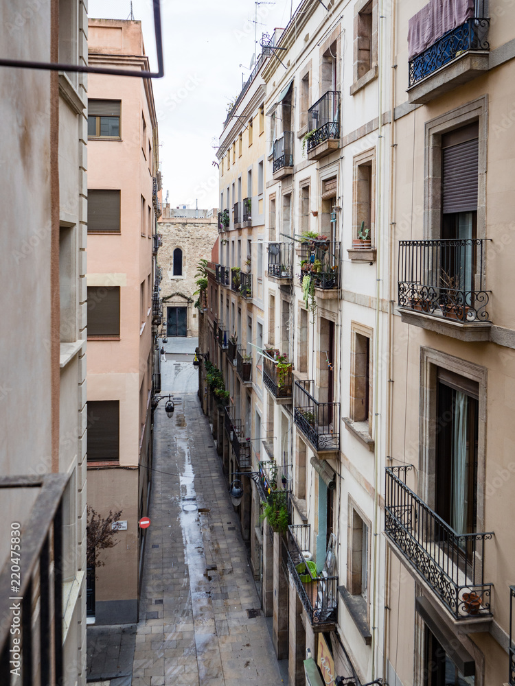 Narrow city street with wrought iron balconies in old town near gothic quarter, Barcelona, Spain on an overcast day