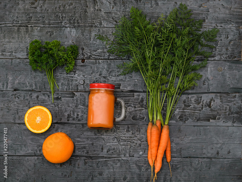 Freshly made carrot smoothie, bunch of carrots and two orange on a rustic table. The view from the top. Flat lay. photo