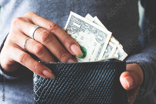 Paper currency in wallet with woman hands.