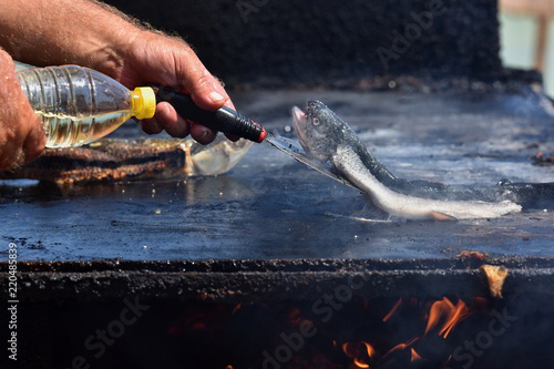 Cooking grilled fish on Vama Veche beach, a non-mainstream tourist destination on the Black Sea coast, near the border with Bulgaria, popular destination for tourists from entire world. photo