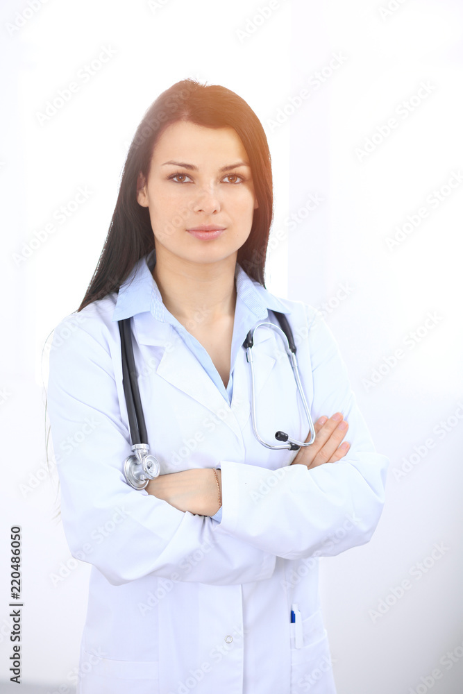 Brunette female doctor standing straight at hospital. Medicine and health care concept Brunette female doctor standing straight at hospital. Medicine and health care concept