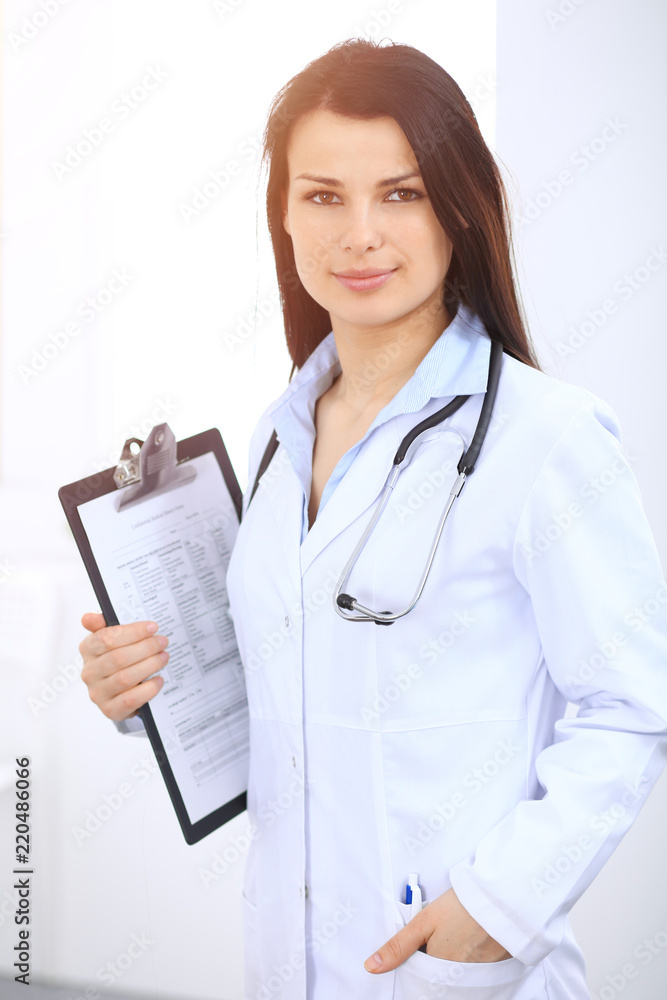 Brunette female doctor standing straight at hospital. Medicine and health care concept Brunette female doctor standing straight at hospital. Medicine and health care concept