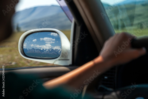 Wallpaper Mural driving car on the mountain road. Guy inside the car driving on the country roadway between fields with brown grass and snowy mountains . Sun is shining. Shoot from the back. Torontodigital.ca