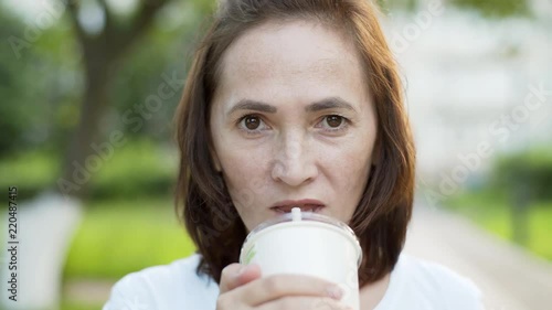 Beautiful woman looking at camera drinking cocktail from glass with straw. photo