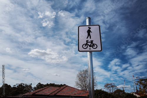 Photography Human and bicycle shared zone sign with house roof and blue sky