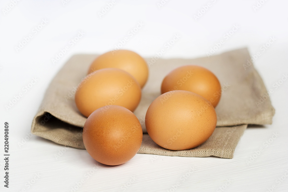 Brown chicken eggs on burlap on a white background