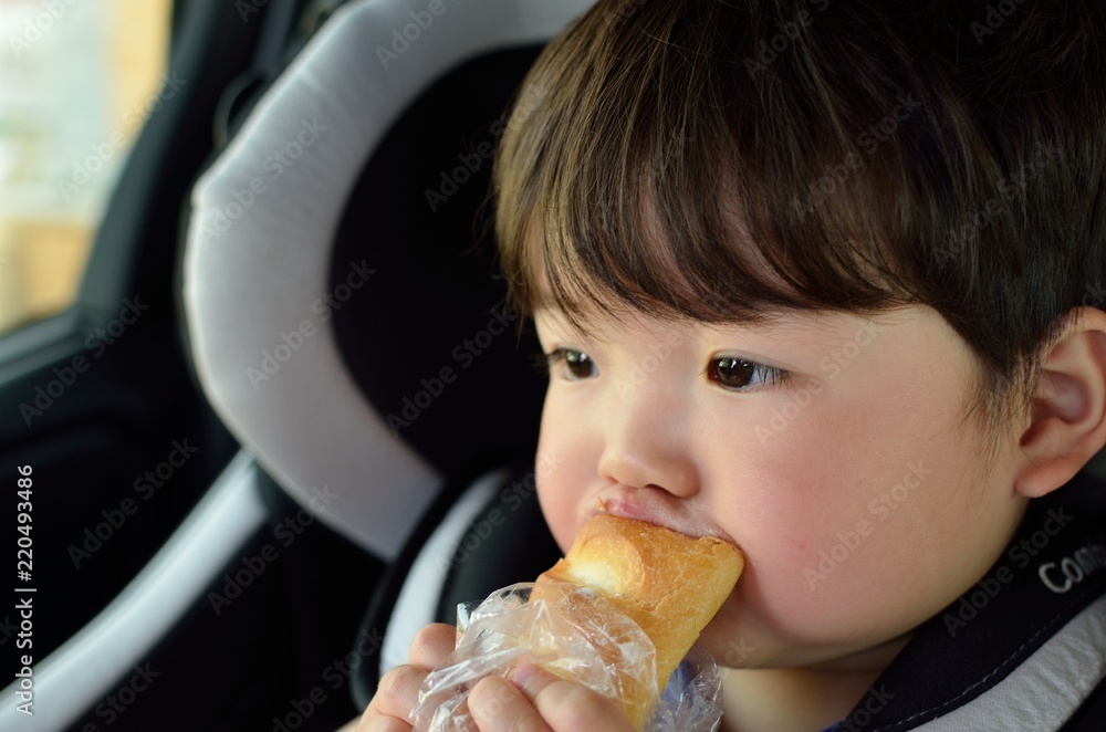 チャイルドシートでパンを食べる子供 Stock Photo | Adobe Stock
