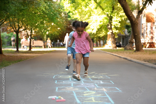 Fotografi Little children playing hopscotch drawn with colorful chalk on asphalt