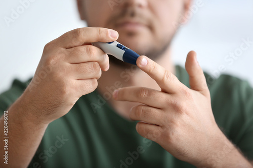 Diabetic man taking blood sample with lancet pen  closeup