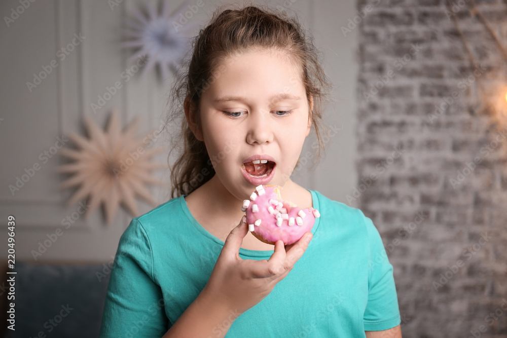 Overweight girl eating doughnut indoors Overweight girl eating doughnut indoors