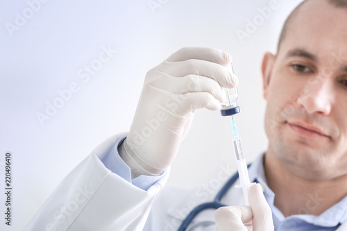 Doctor with syringe and vial, closeup. Vaccination day