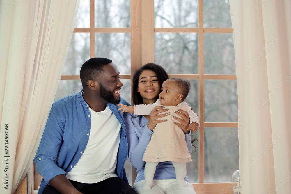 Cute African-American baby with parents at home