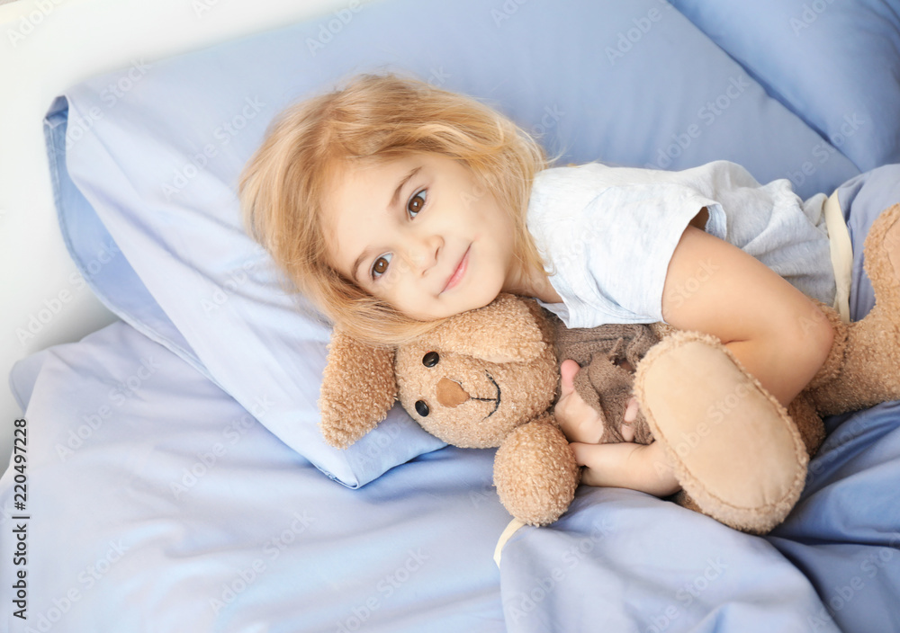 Cute little girl with bunny toy lying in bed at home Cute little girl with bunny toy lying in bed at home