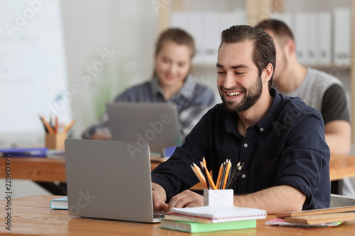 Male student with laptop doing homework in classroom